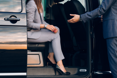 man in a suit helping a woman exit a van